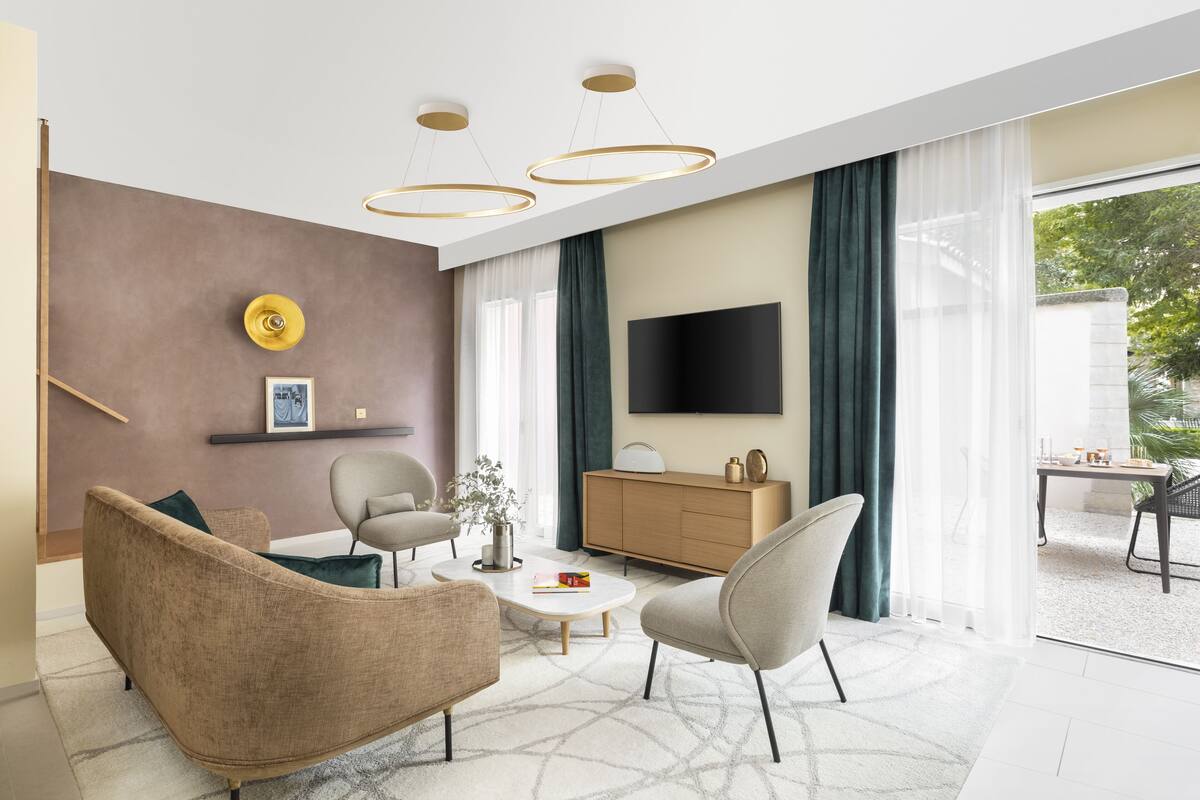 A modern living room with a sofa, armchairs, a coffee table, and a TV.