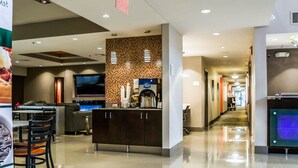 A modern hotel lobby with a seating area, a coffee station, and a long corridor leading to other areas. - Quality Suites Fort Myers I-75 (Fort Myers)