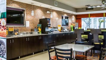 A modern kitchen with a brick backsplash, a coffee machine, and a flat-screen TV.