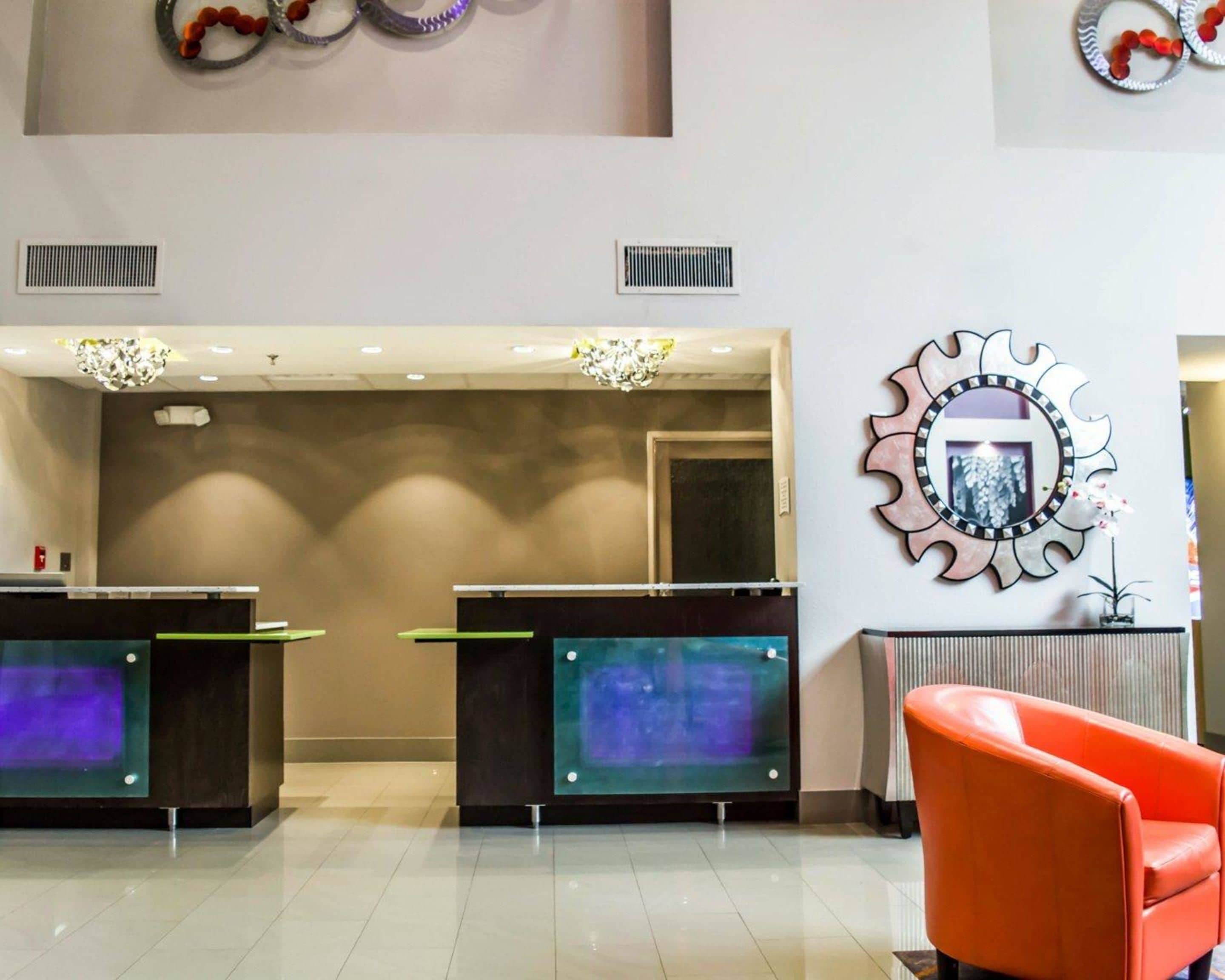 A reception area with two counters, a modern chandelier, a decorative mirror, and a red chair.