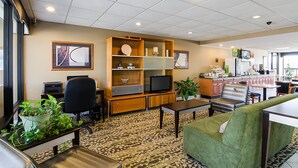 A hotel room with a kitchenette, a dining area, a living room with a sofa and a TV, and a large window. - Quality Inn Troutville - Roanoke North (Troutville)