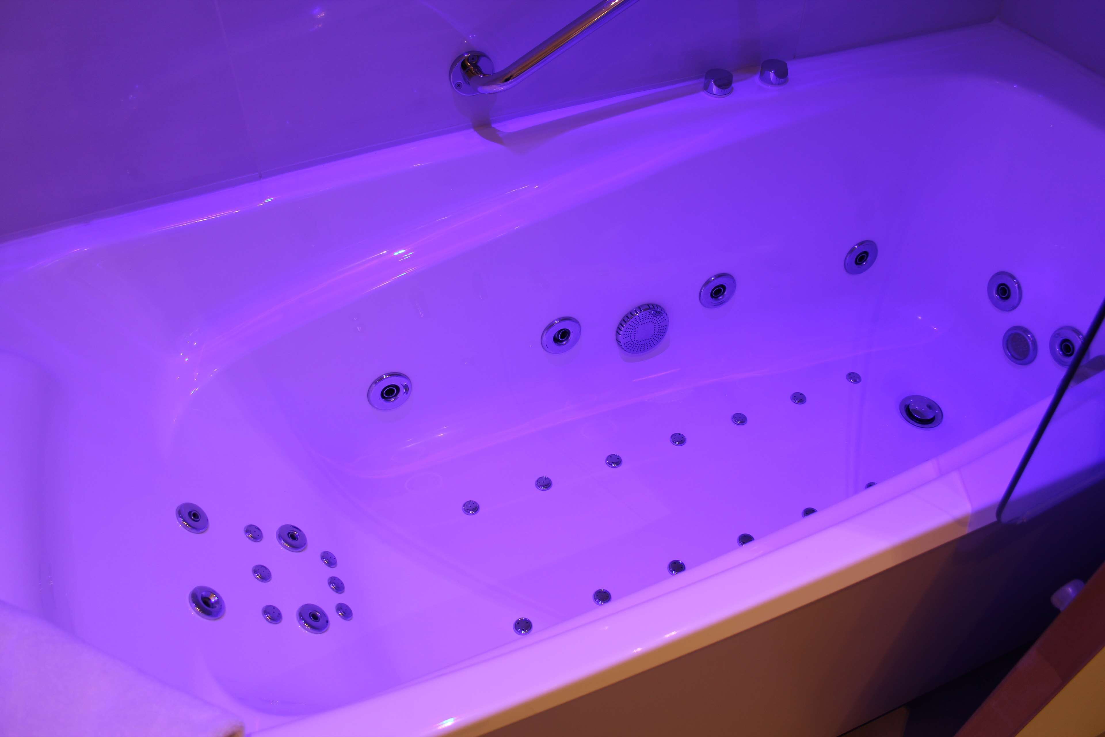 A bathtub with multiple jets and a handheld showerhead, indicating a spa or relaxation feature.