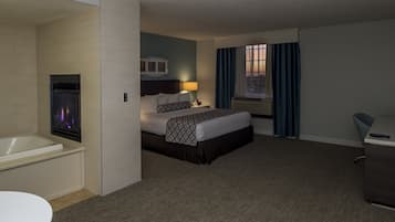 Habitación de hotel con cama, escritorio, silla, baño con bañera y ventana con cortinas.
