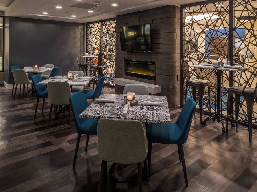 A restaurant interior with tables, chairs, a TV, and a patterned wall.