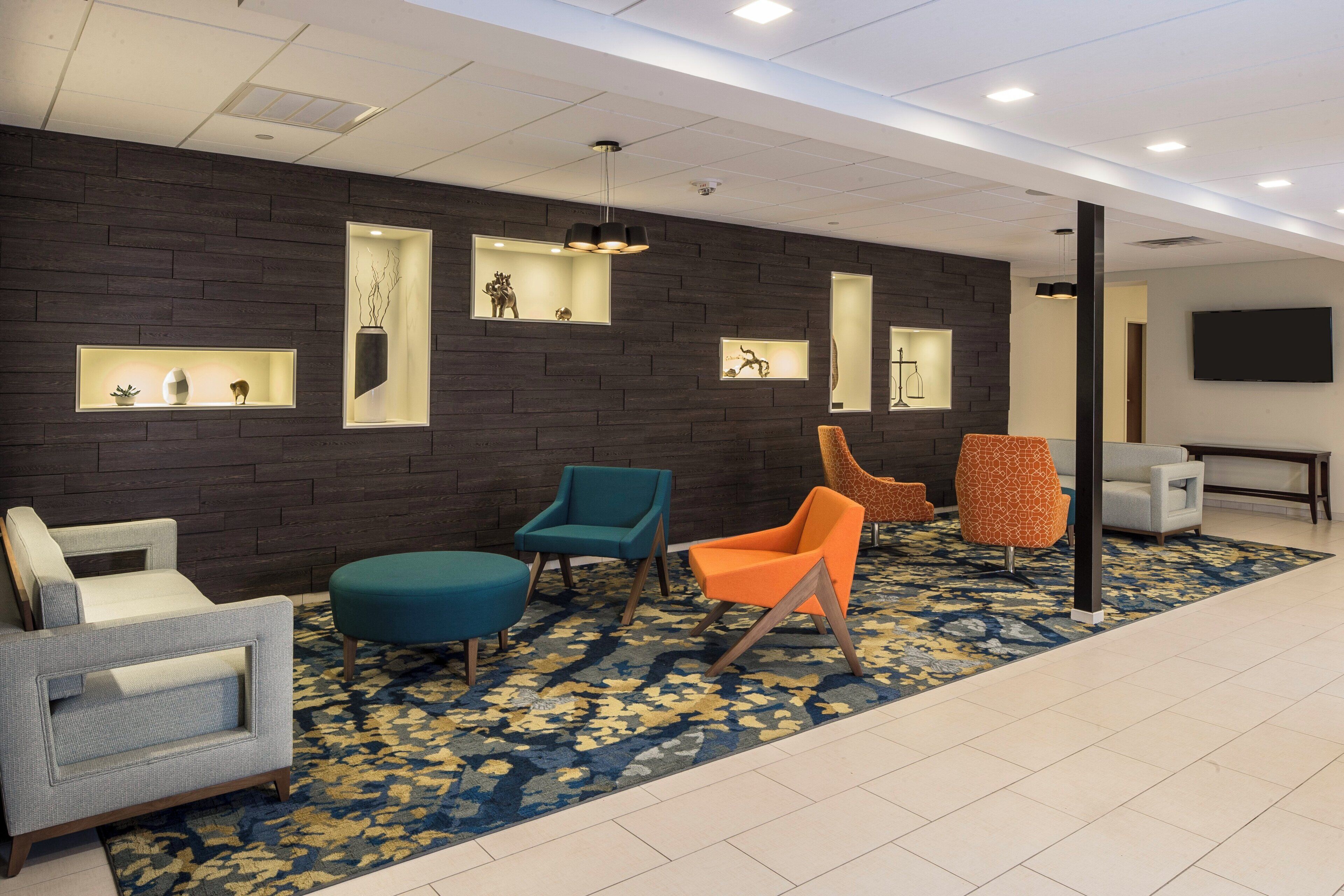 A lobby with a dark brick wall, multiple seating areas, and a patterned carpet.