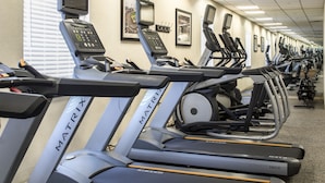 A row of treadmills with digital displays and control panels, arranged in a gym with a tiled floor and framed pictures on the wall. - Crowne Plaza Suites Pittsburgh South by IHG (Bethel Park)