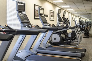 A row of treadmills with digital displays and control panels, arranged in a gym with a tiled floor and framed pictures on the wall. - Crowne Plaza Suites Pittsburgh South by IHG (Bethel Park)