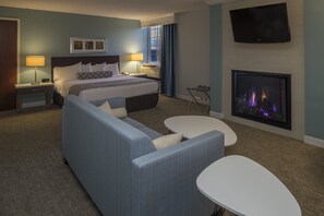 A hotel room with a bed, a sofa, a small table, a TV, and a fireplace. - Crowne Plaza Suites Pittsburgh South by IHG (Bethel Park)