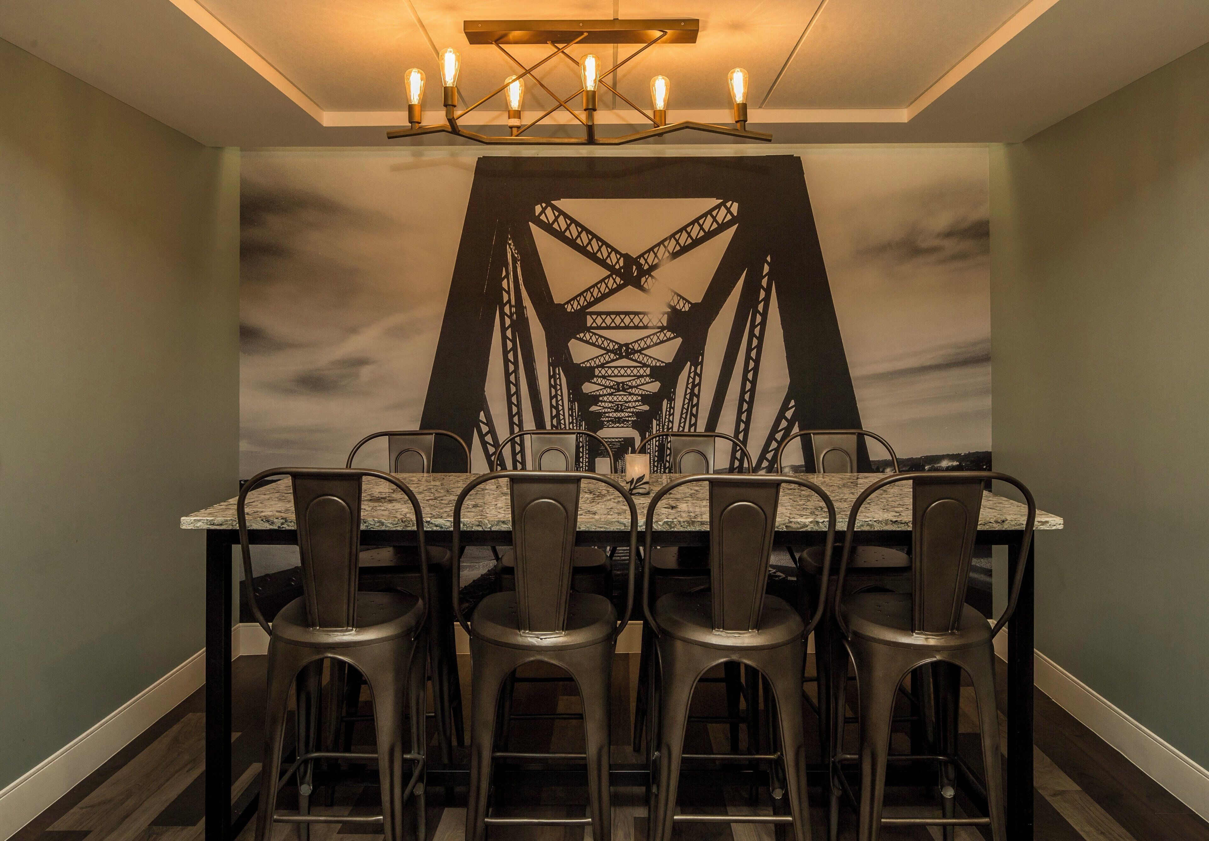 Un espace repas comprenant une table et des chaises, un lustre et une fresque murale.