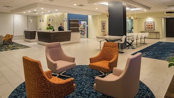 A hotel lobby with a reception desk, seating area, and a bar.