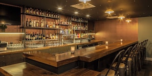 A bar area with shelves of bottles, a cash register, and bar stools. - Crowne Plaza Suites Pittsburgh South by IHG (Bethel Park)