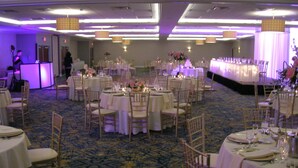 A banquet hall with round tables set for dining, chairs, and a stage area. - Crowne Plaza Suites Pittsburgh South by IHG (Bethel Park)
