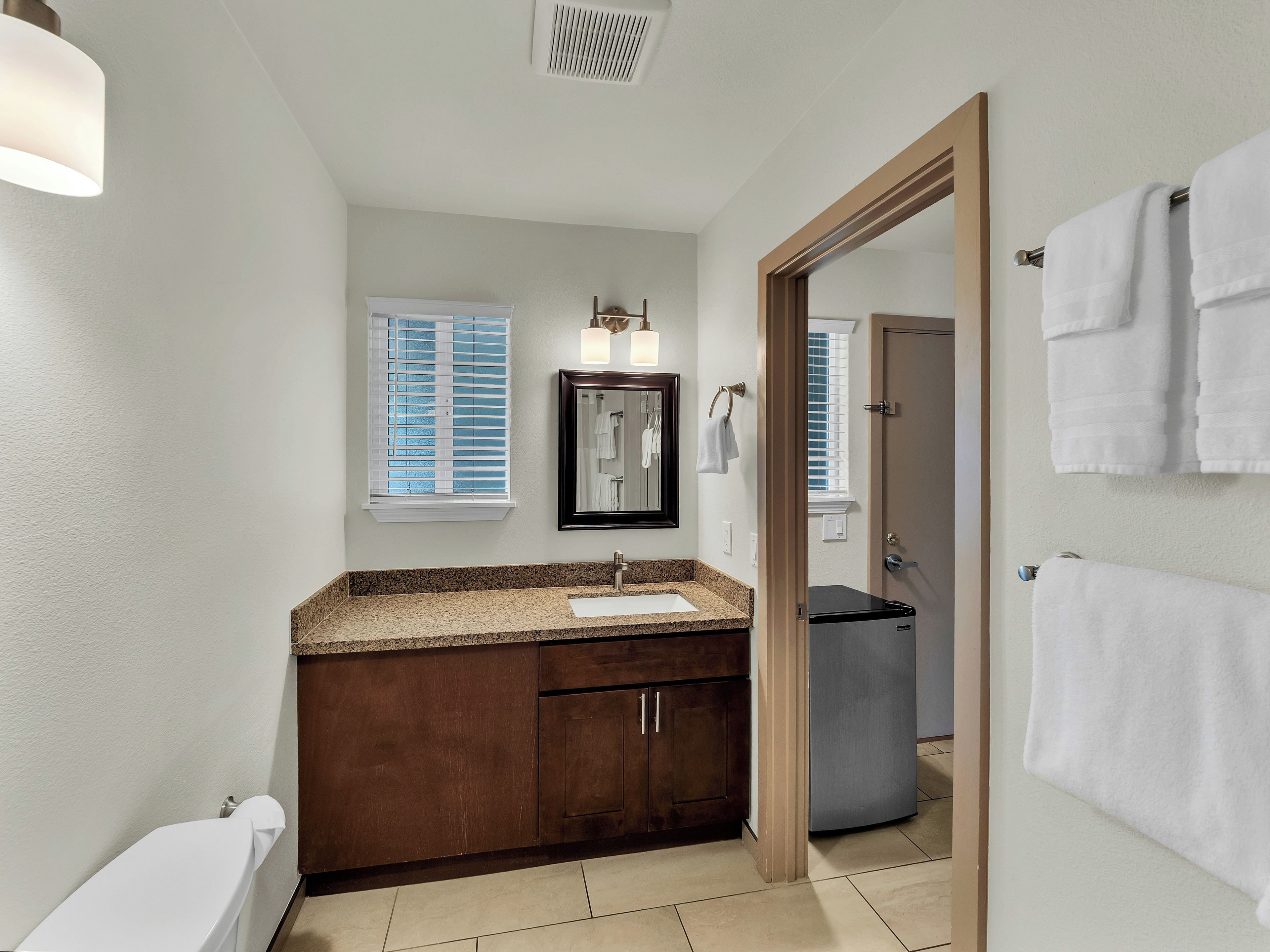 A bathroom with a sink, mirror, and towel rack.