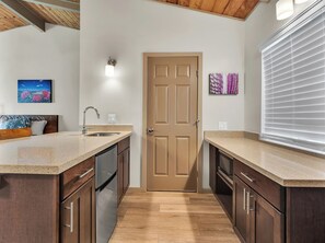 A kitchen with a double sink, wooden cabinets, a stainless steel refrigerator, and a wooden ceiling. - Castle Waimea Country Lodge (Kamuela)