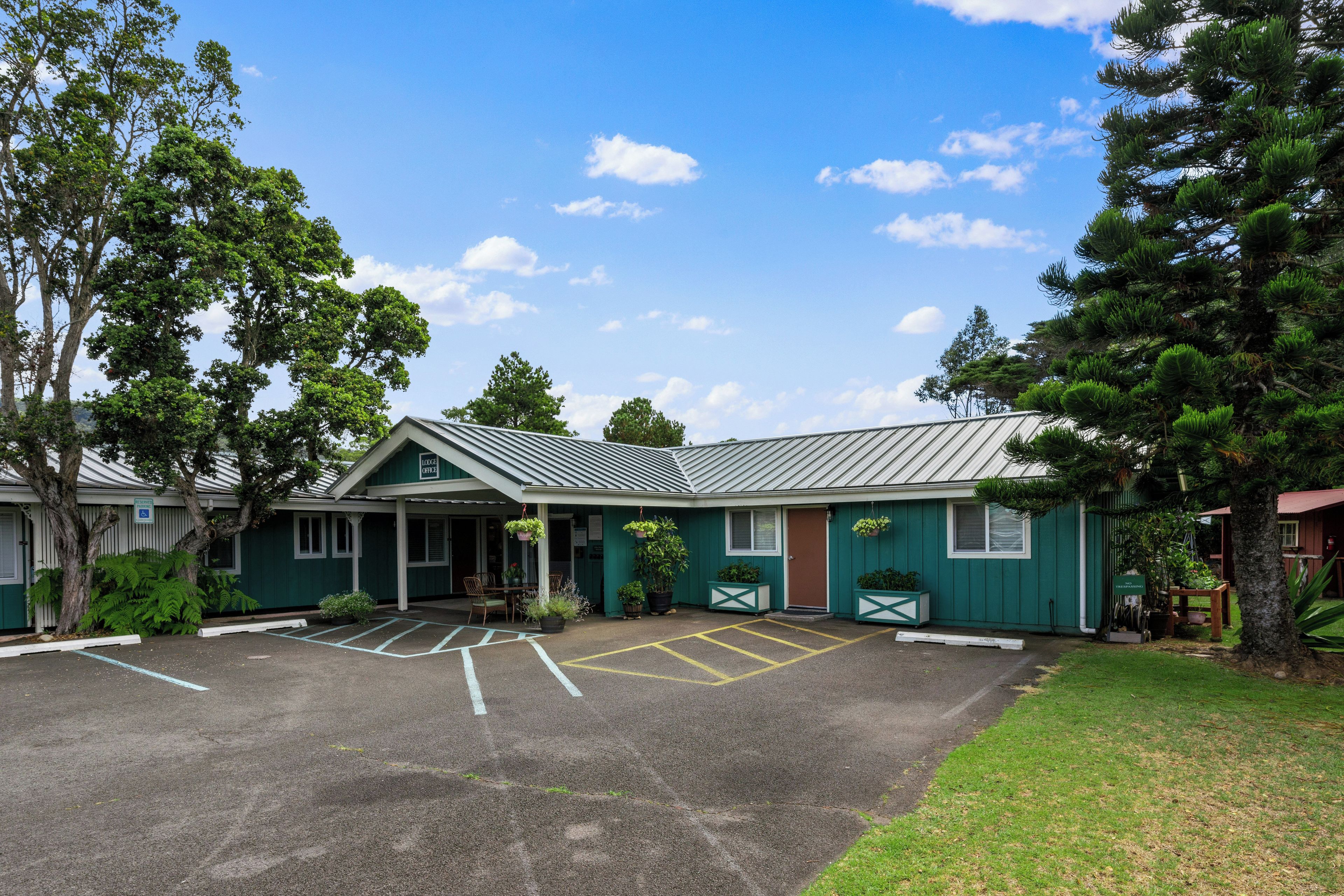 A lodge with a parking area, a covered entrance, and a green building with a metal roof.