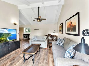 A living room with a television, sofa, coffee table, and ceiling fan. - Castle Waimea Country Lodge (Kamuela)