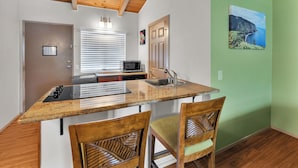 A kitchen with a wooden ceiling, a built-in microwave, a sink, and two chairs. - Castle Waimea Country Lodge (Kamuela)