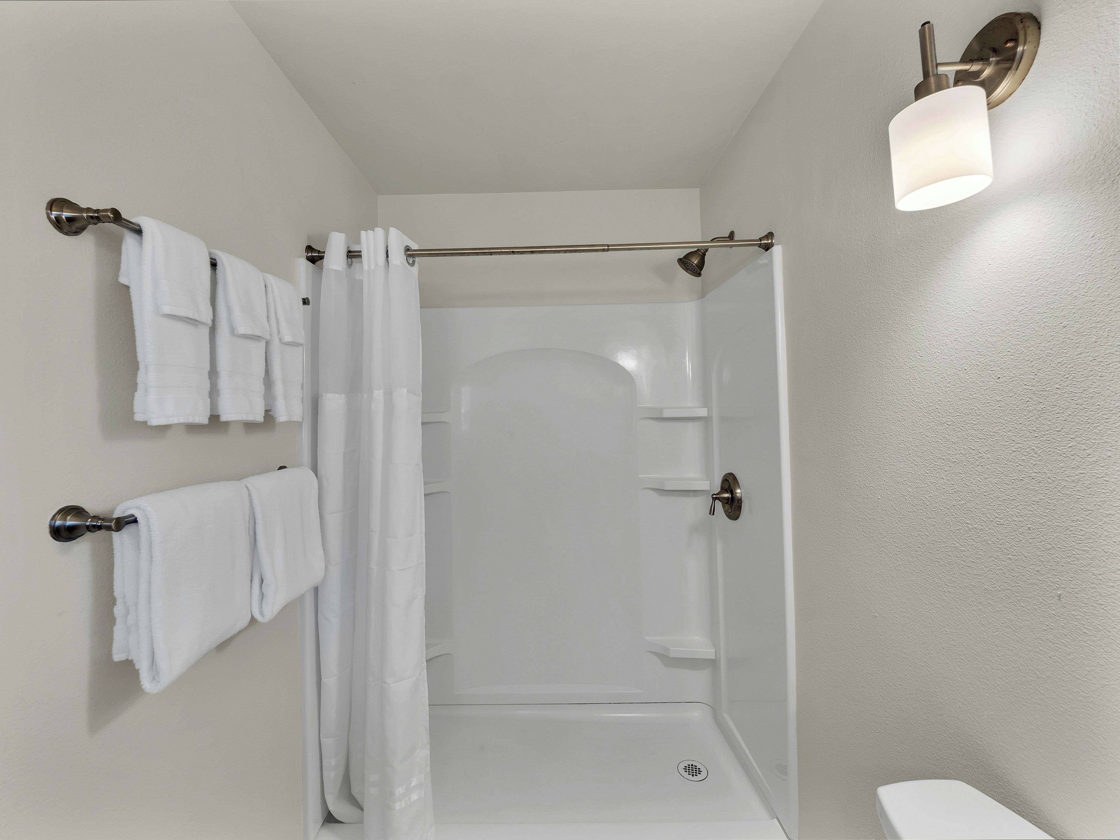 Un baño con ducha, inodoro y toallero con toallas dobladas.