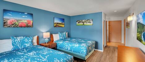 A bedroom with two beds, a nightstand, and a wooden dresser.