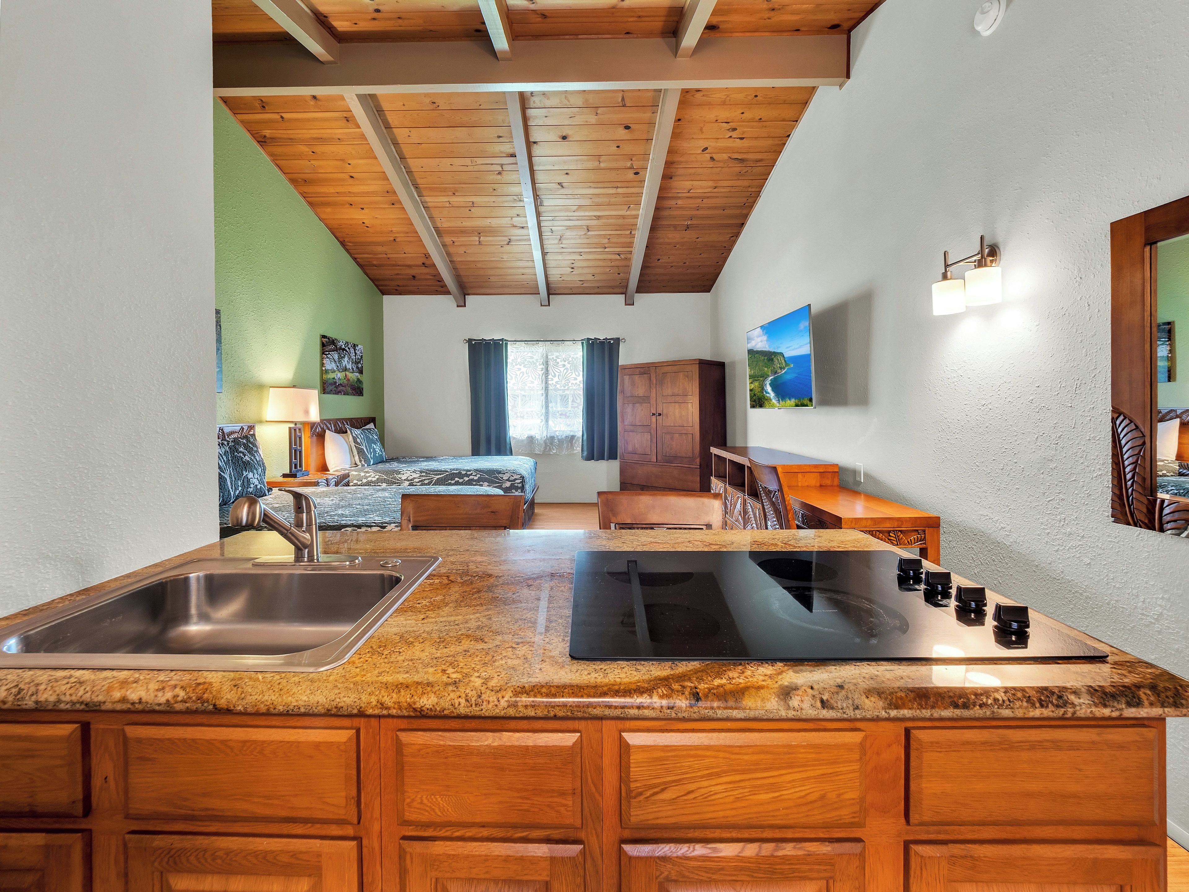 Una cocina con encimeras de granito, gabinetes de madera, un fregadero y una estufa.