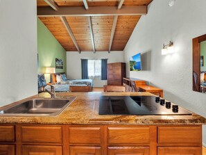 A kitchen with granite countertops, wooden cabinets, a sink, and a stove. - Castle Waimea Country Lodge (Kamuela)