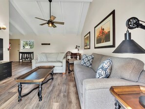 A living room with a sofa, a coffee table, a ceiling fan, and artwork on the walls. - Castle Waimea Country Lodge (Kamuela)