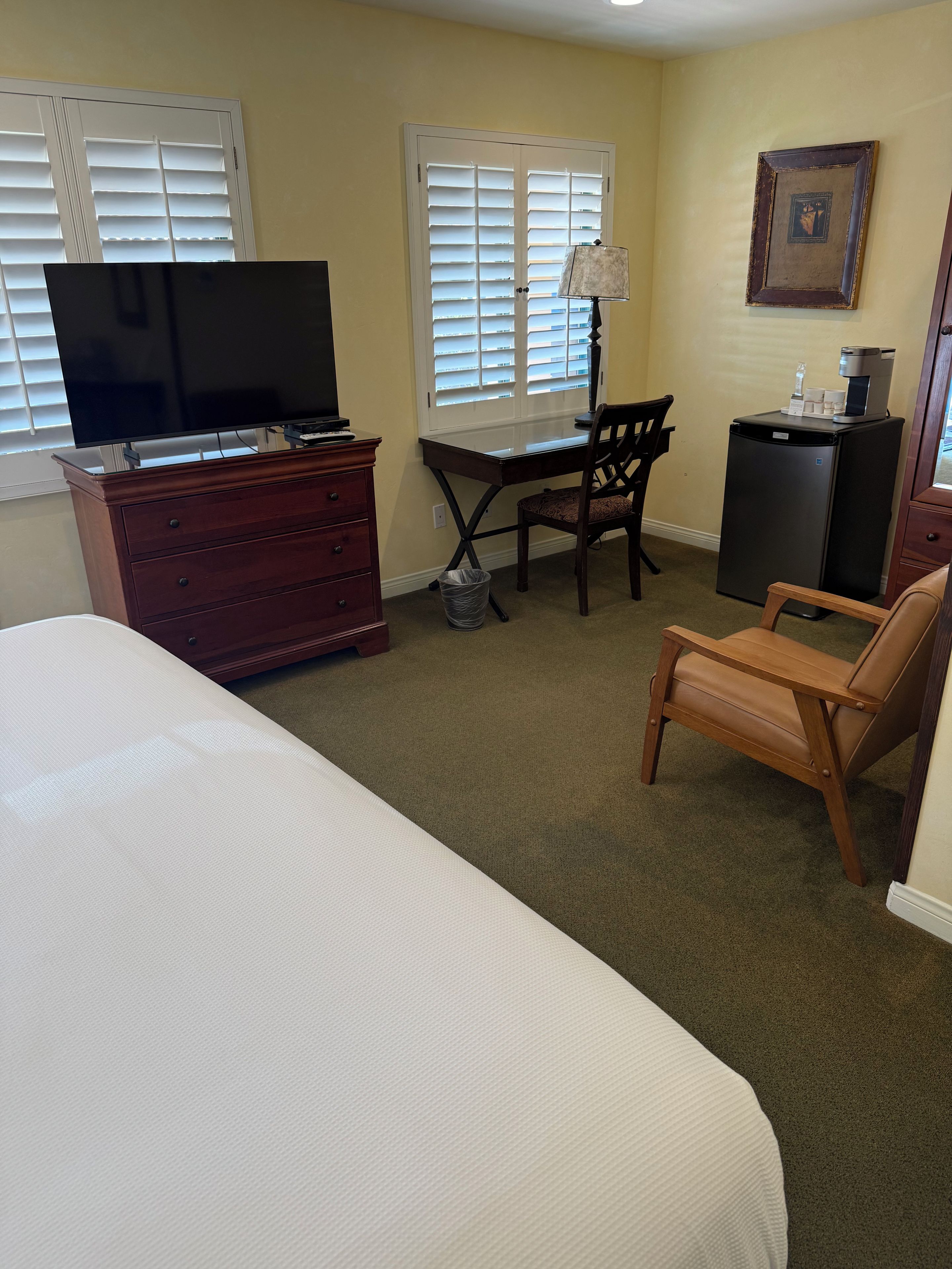 Une chambre d’hôtel équipée d’un lit, d’un bureau, d’une télévision, d’une chaise, d’une commode et d’un réfrigérateur.