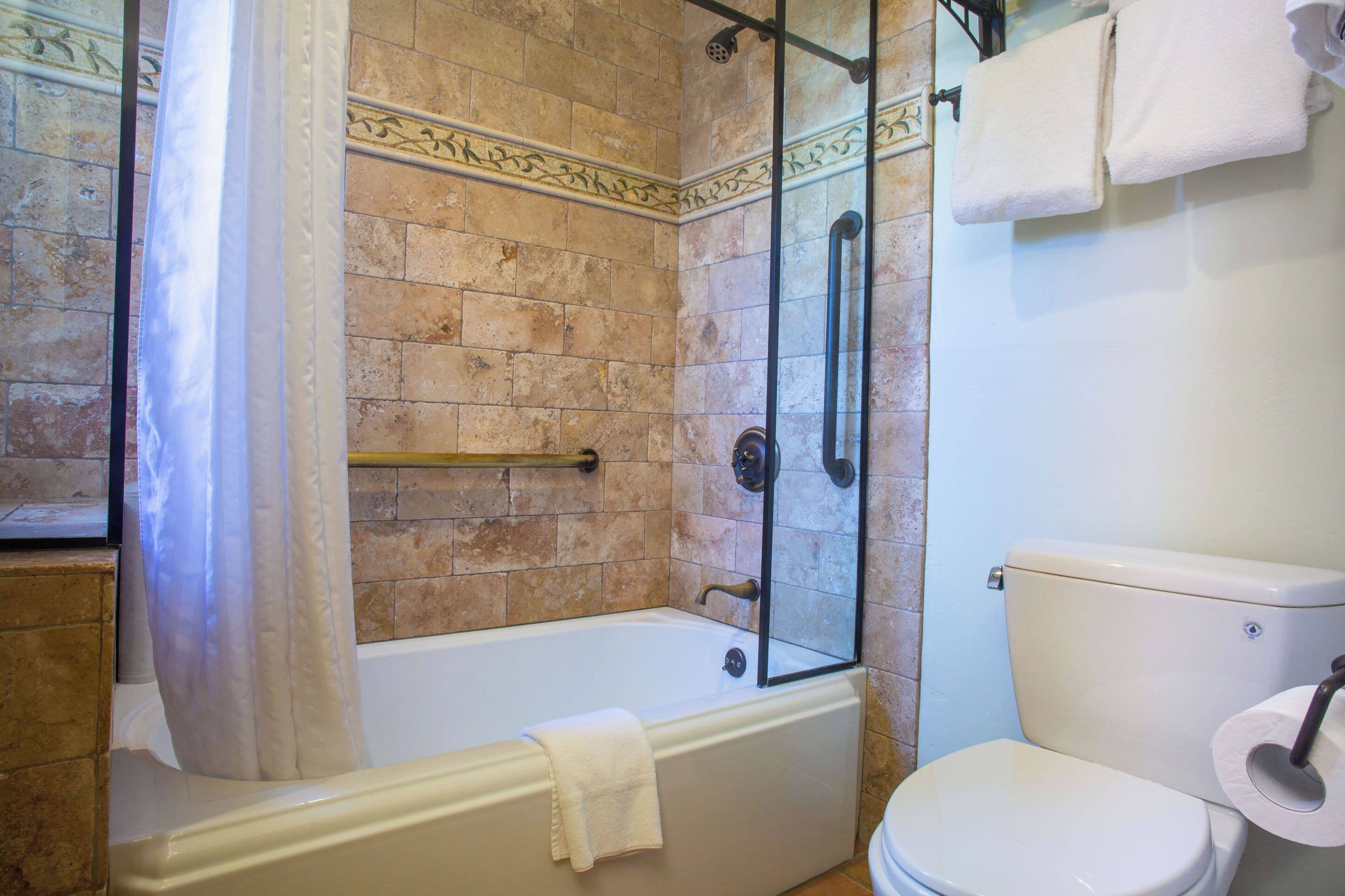 A bathroom with a bathtub, a glass-enclosed shower, and a toilet.