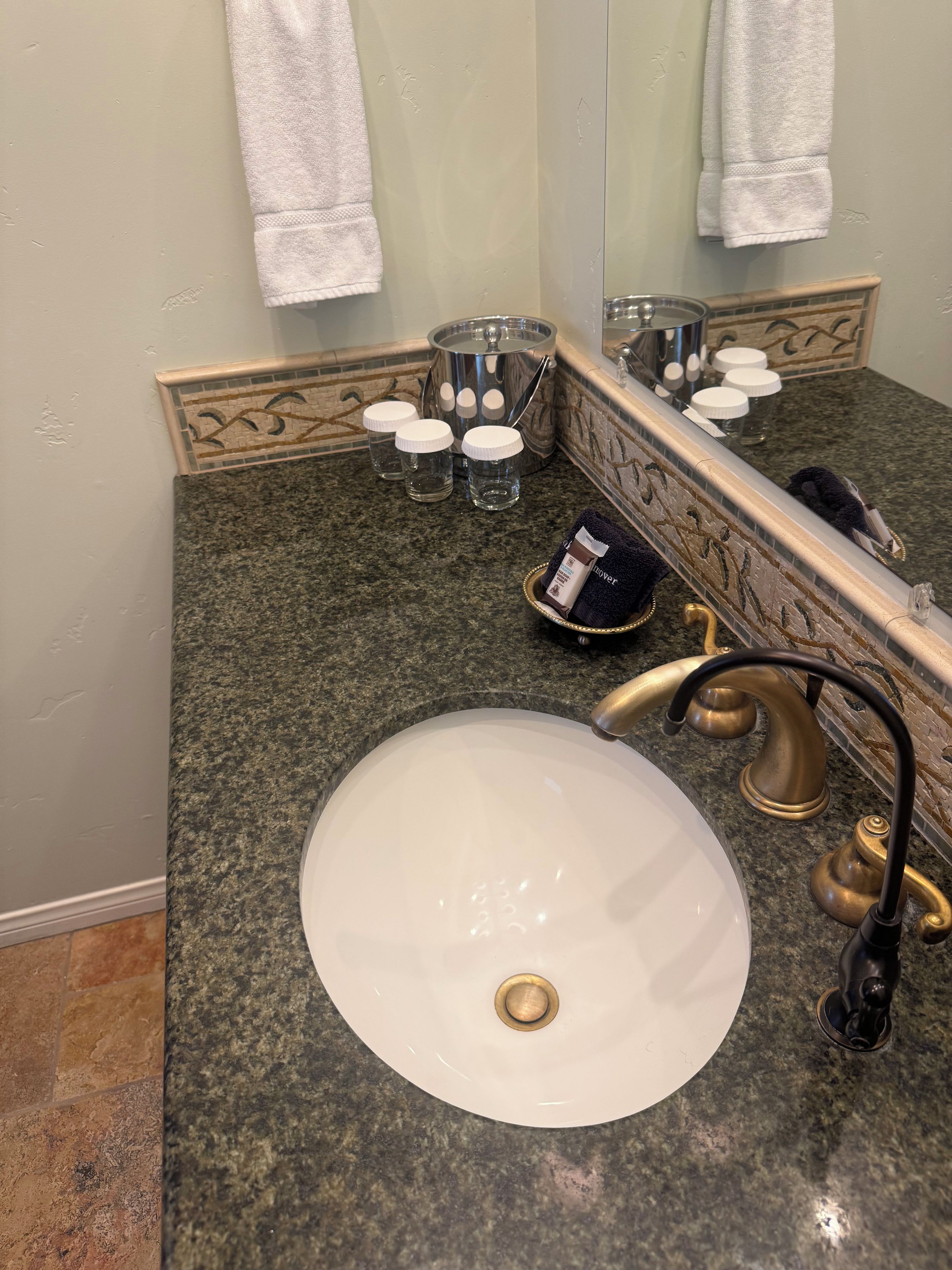 A bathroom with a granite countertop, a white sink, and a mirror.