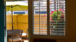 A room with a sliding glass door leading to a patio area with a yellow fence and a table with chairs. - Castillo Inn at the Beach (Santa Barbara)