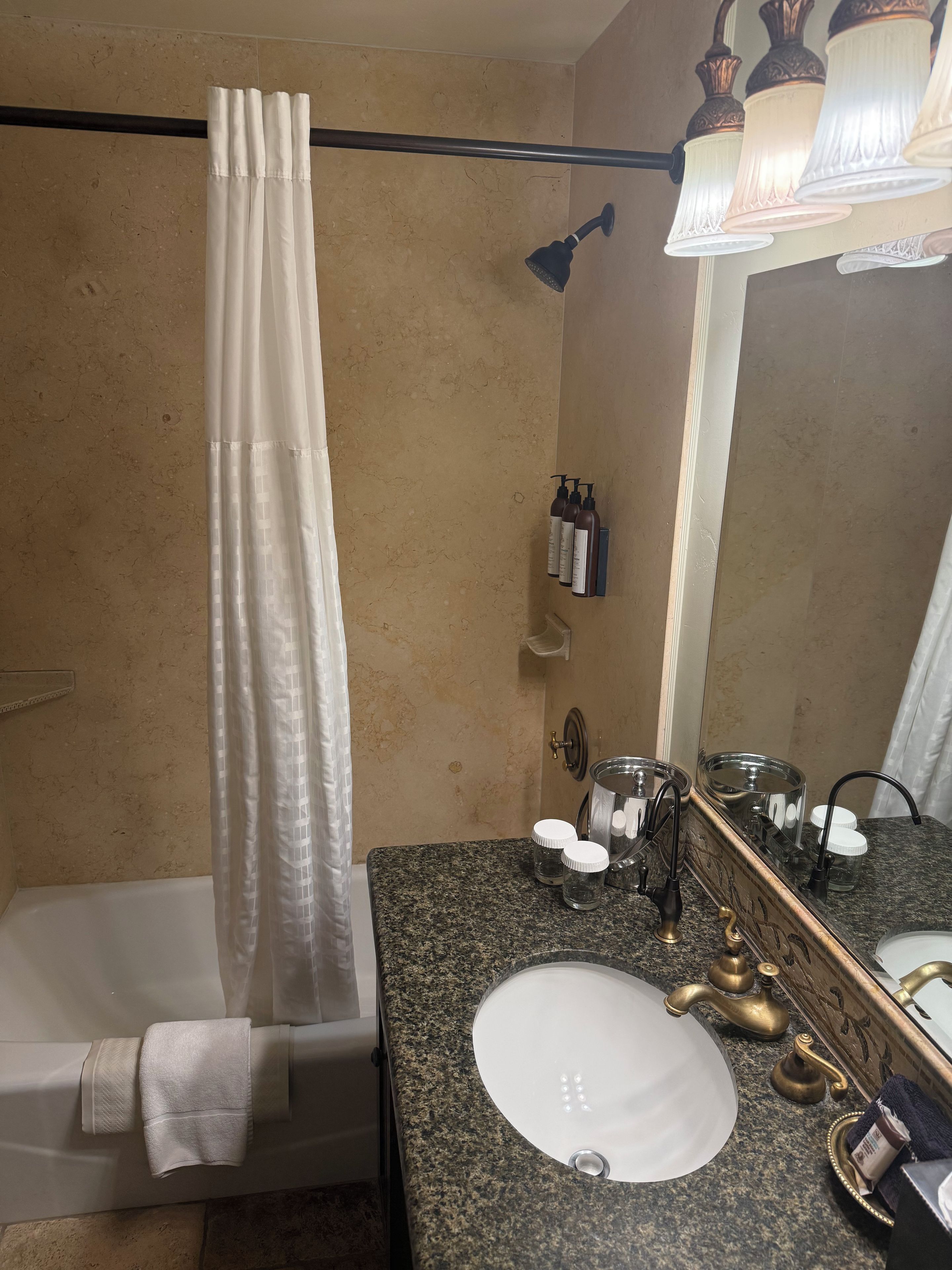 Une salle de bain avec une baignoire, un lavabo avec un robinet doré, un miroir et un rideau de douche.