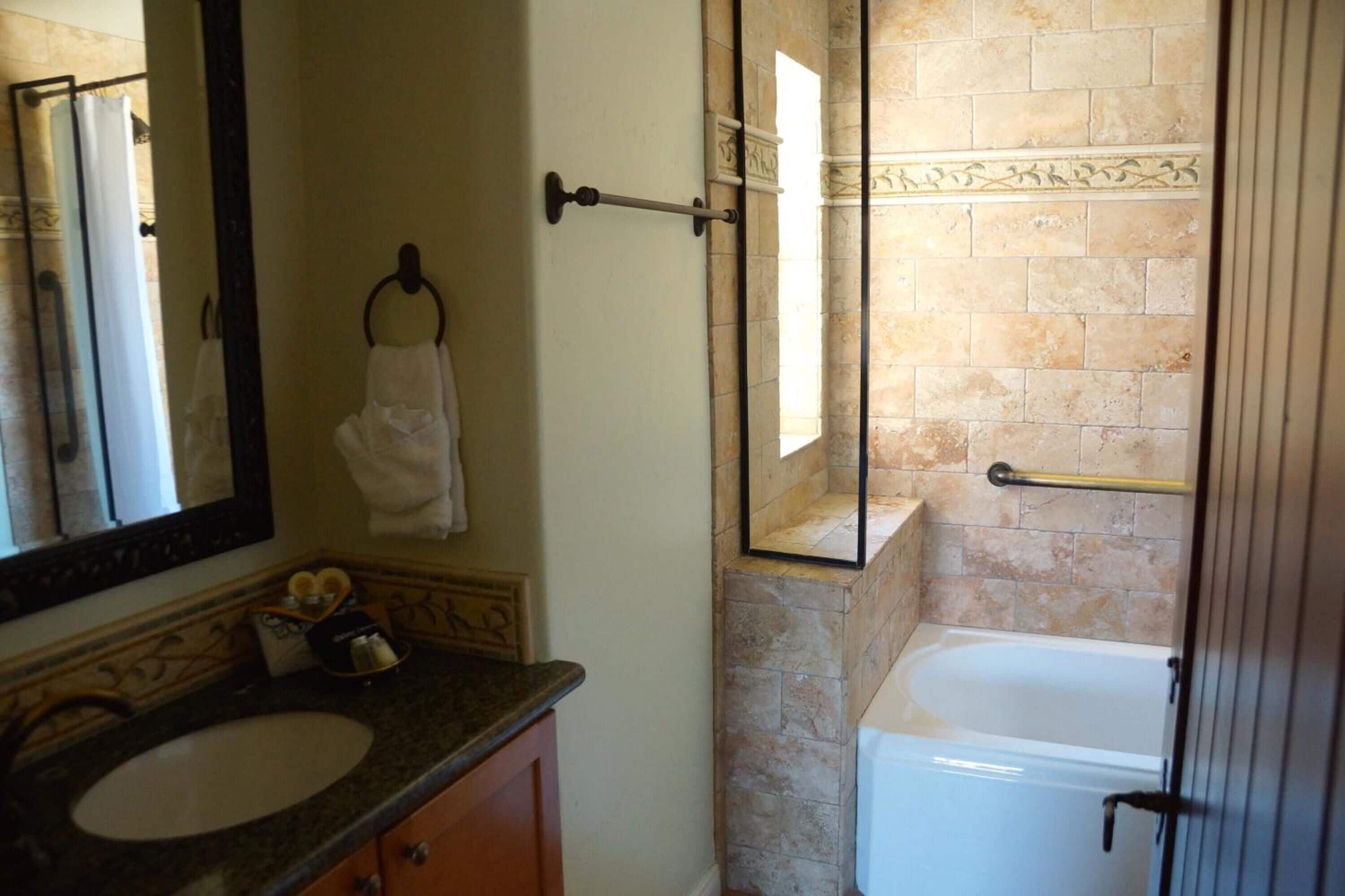 Une salle de bain avec un lavabo en marbre, une cabine de douche en verre et une baignoire blanche.