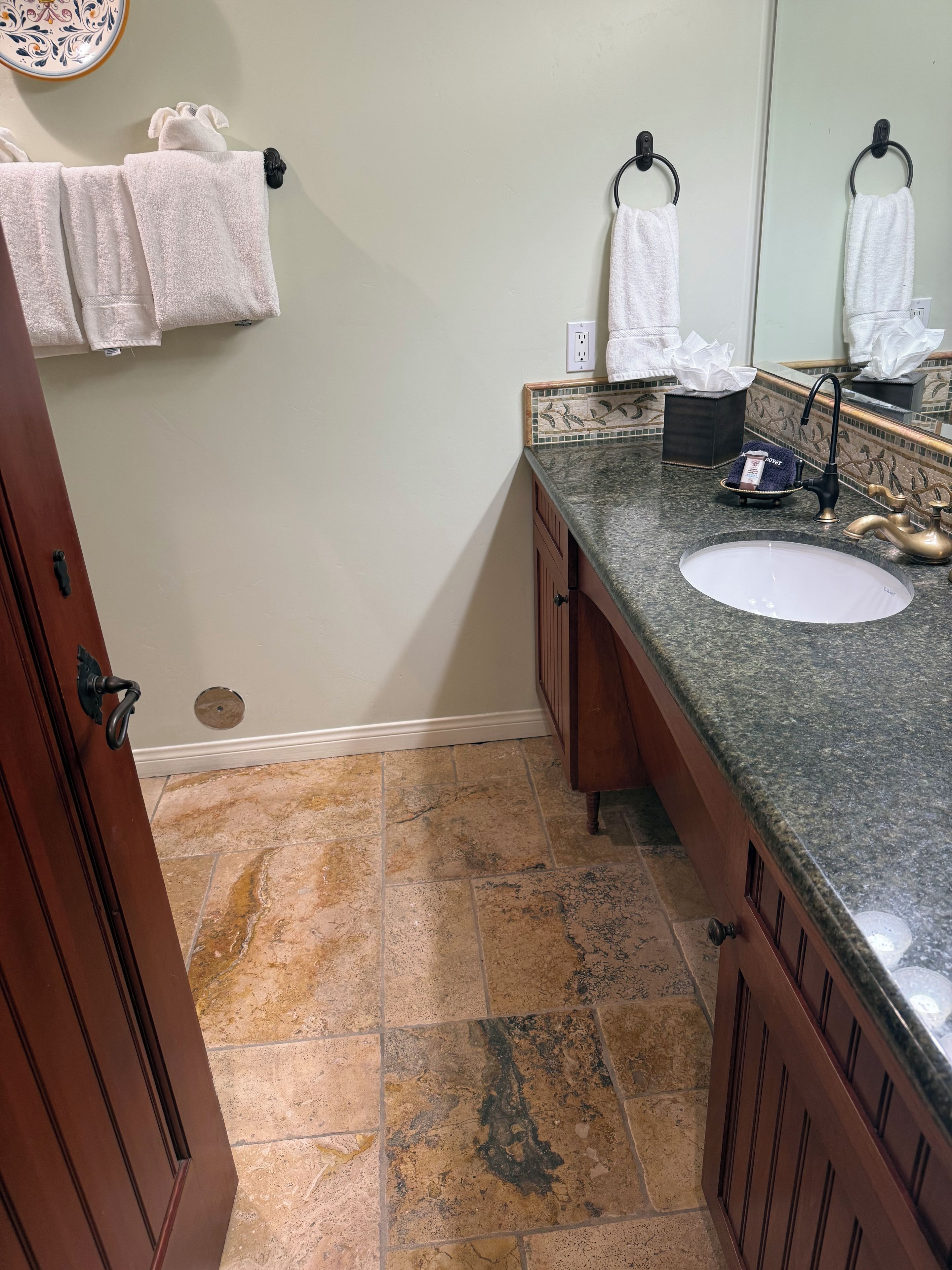 A bathroom with a granite countertop, a sink, a mirror, and a towel rack.