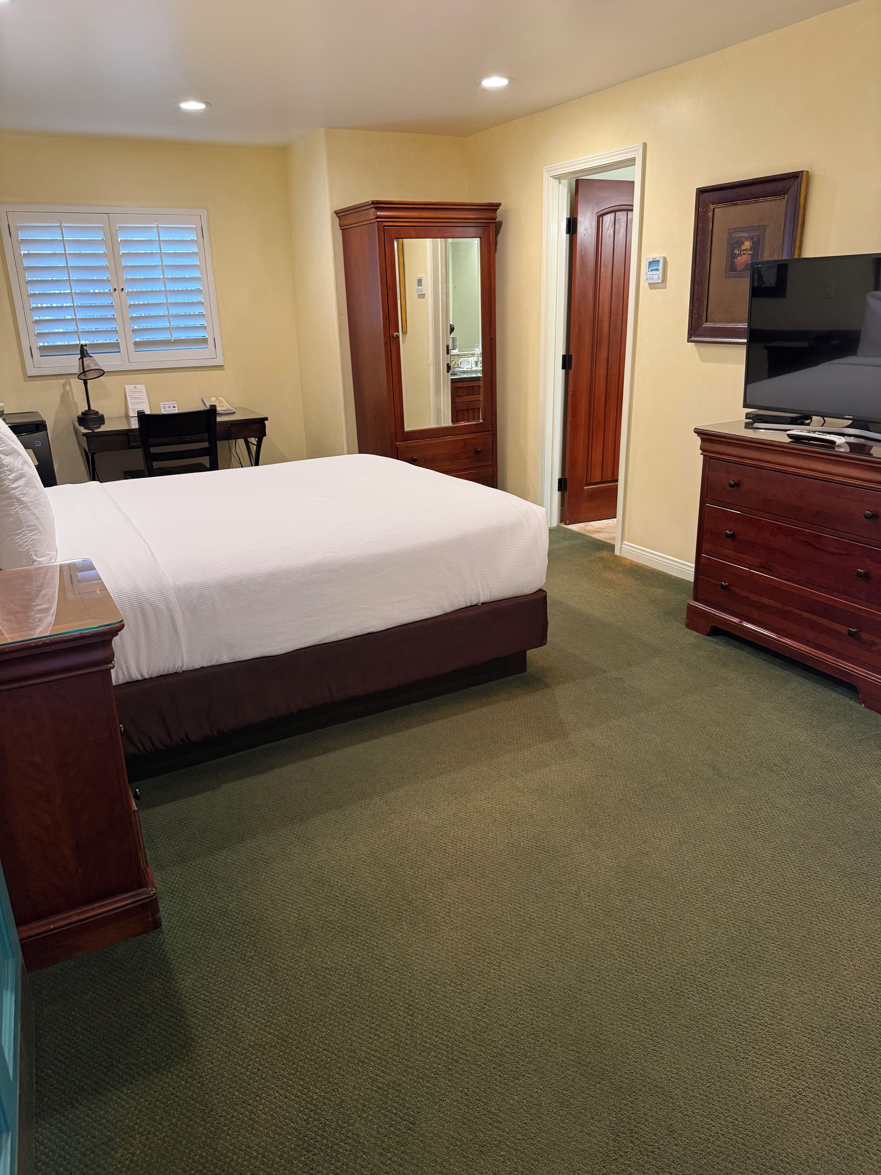 Une chambre d’hôtel comprenant un lit, une commode, un bureau, une chaise et un téléviseur.