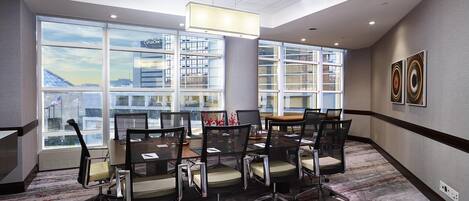 A conference room with a large table, chairs, and a view of the city through large windows.