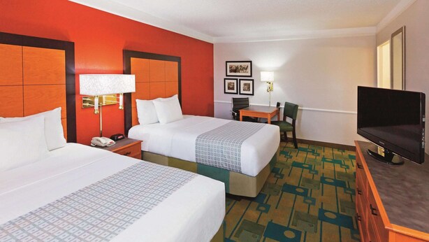 A hotel room with two beds, a desk, a chair, a TV, and a lamp. - Baymont by Wyndham Lubbock - Downtown Civic Center (Lubbock)