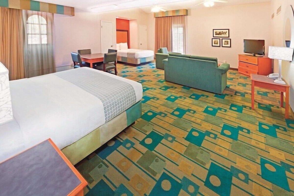 Ein Hotelzimmer mit Bett, Sofa, Schreibtisch, Fernseher und Lampe.