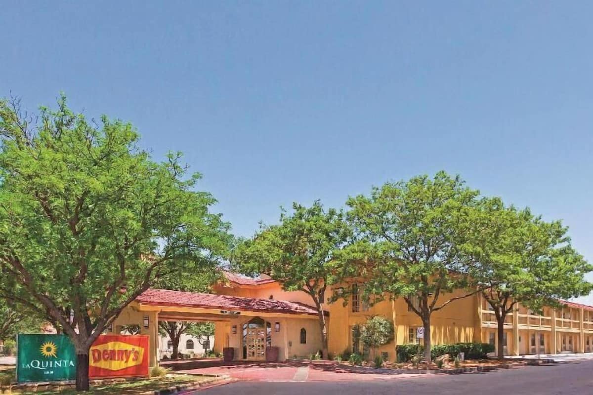 Un hôtel avec un toit recouvert de tuiles rouges, une enseigne « La Quinta » et un restaurant Denny’s.