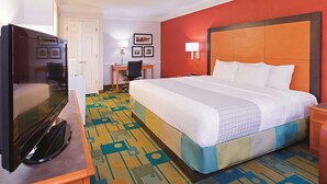 A hotel room with a large bed, a desk with a chair, a television, and a patterned carpet. - Baymont by Wyndham Lubbock - Downtown Civic Center (Lubbock)