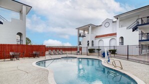 A swimming pool with lounge chairs and a red fence.