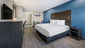 A modern hotel room with a large bed, a desk, and a TV.