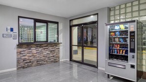 Een modern interieur met een automaat, een glazen deur en een accentmuur van baksteen.