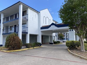 A multi-story building with a white facade, balconies, and a covered entrance. - SureStay Hotel by Best Western Spring North Houston (Spring)