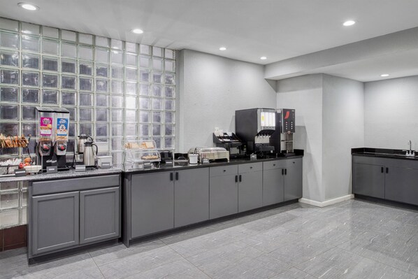 A modern kitchen with grey cabinets, a coffee station, and a large window.