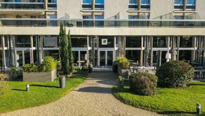 Ein modernes Gebäude mit Glasfassade, Sitzgelegenheiten im Freien und gepflegter Bepflanzung.
