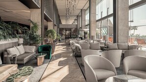 Un vestíbulo amplio con mobiliario moderno, ventanas grandes y plantas de interior.