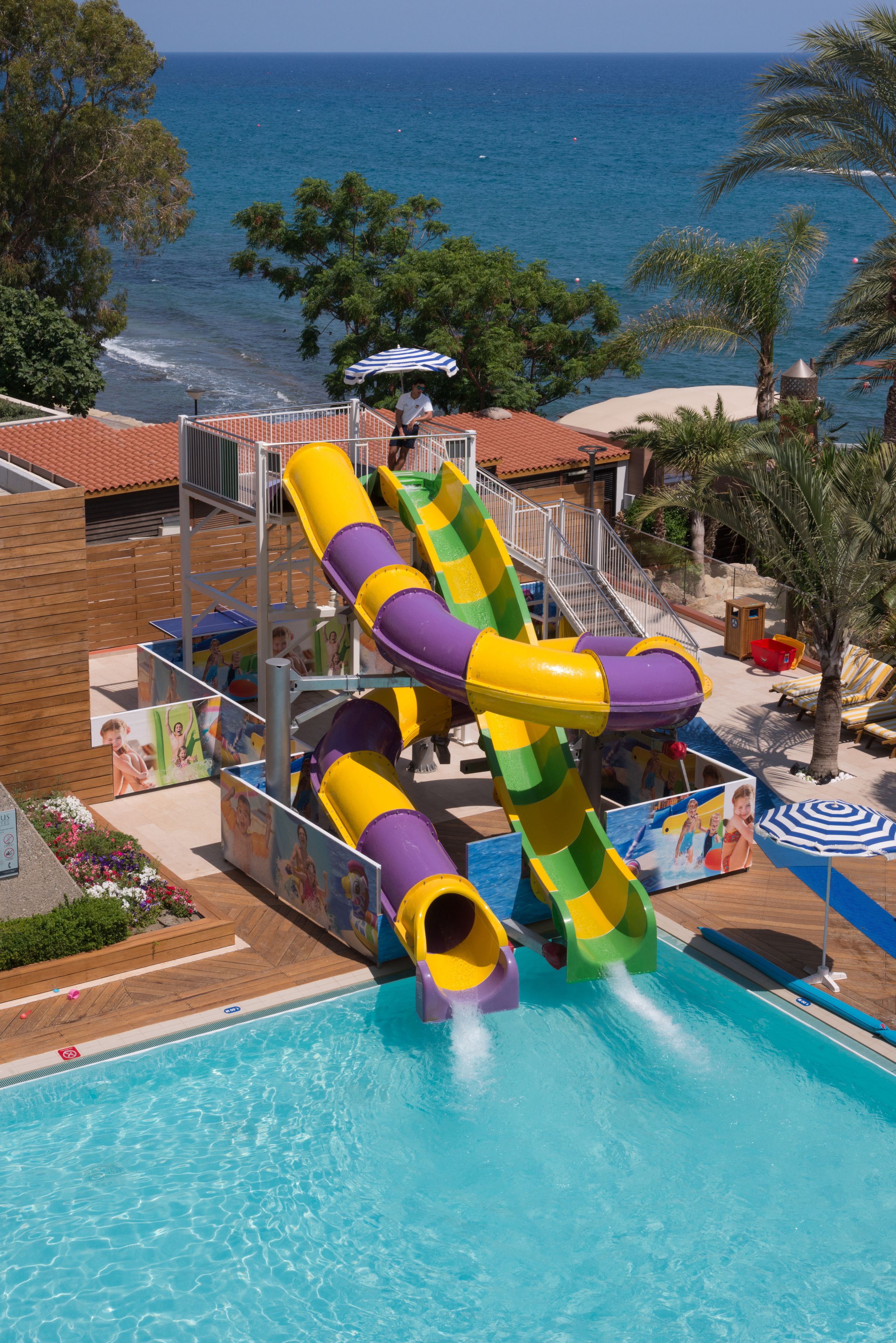 Un parc aquatique doté d’un grand toboggan multicolore, d’une piscine et d’une vue sur l’océan.