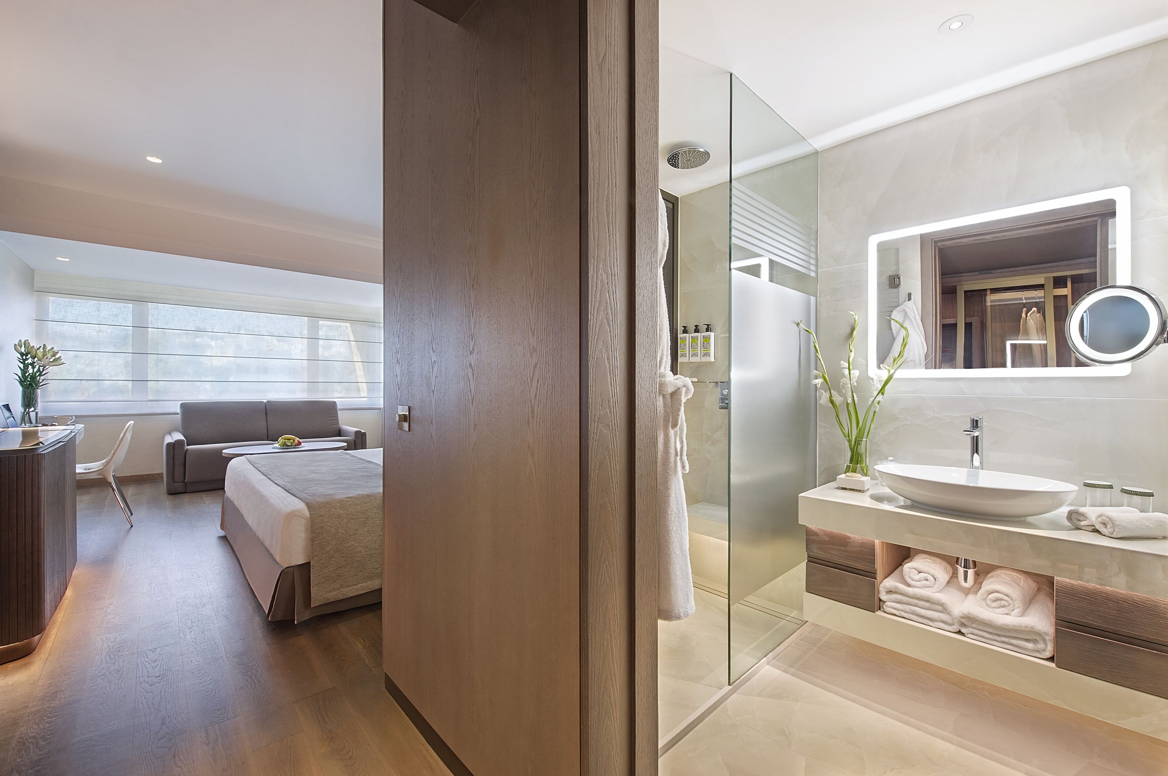Habitación de hotel moderna con una cama grande, una mesita de noche, un escritorio y vistas al exterior.