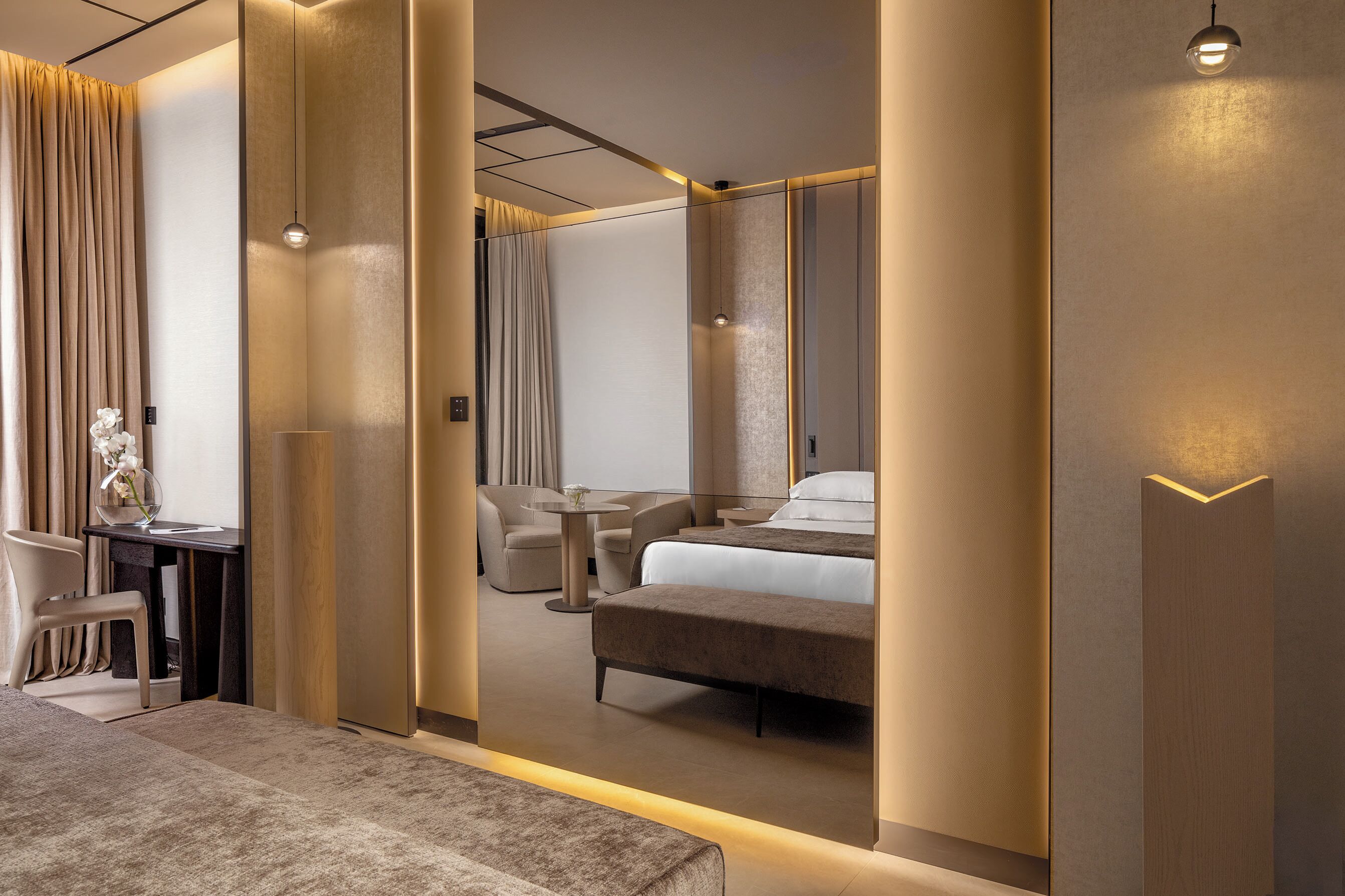 A modern hotel room with a large bed, a desk, and a seating area.