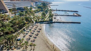 Ett hotell vid kusten med ett område vid stranden, inklusive solstolar och parasoller, och utsikt över havet.